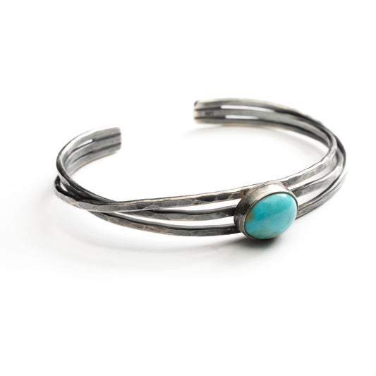 3 hand hammered silver bands hold a turquoise stone